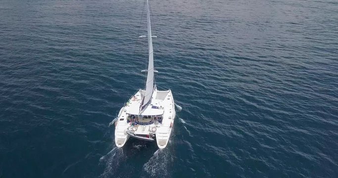 A beautiful view of yacht sailing alone on the blue waters of Ceningen island, Bali, Indonesia with infinite horizon and blue sky in the background. Rotating aerial.