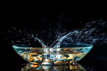 Water splashes on a black background. The stone drops water and creates splashes. Frozen motion.