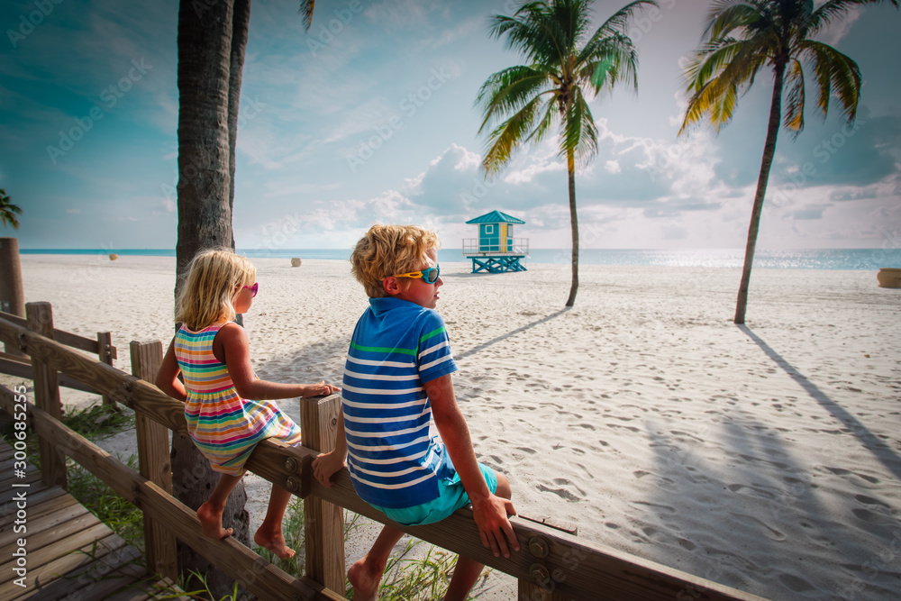 Poster boy and girl looking at tropical beach with palms, family on vacation in florida