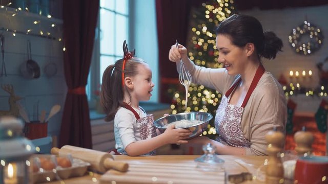Merry Christmas and Happy Holidays. Family preparation holiday food. Mother and daughter cooking cookies.