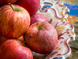 Big plate with red and yellow ripe apples on a wooden vintage table, close-up