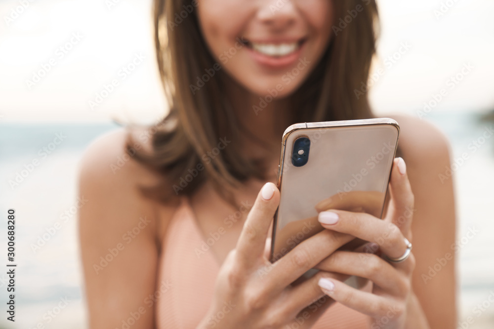 Poster Cropped image of nice woman smiling and using cellphone