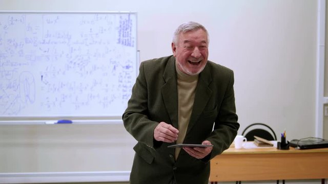 Happy professor with tablet gives a lecture.