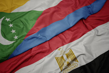 waving colorful flag of egypt and national flag of comoros.