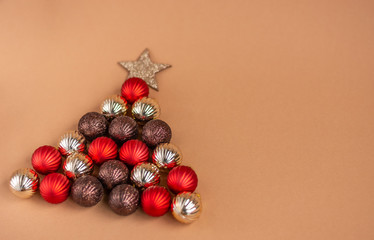 Christmas tree made of red, silver and brown balls on a beige background. Creative christmas concept.