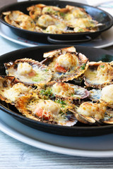 Baked scallops with cheese and spicy sauce. Delicate clam is a real pleasure. Romantic dinner at a Spanish fish restaurant. Mallorca Island, Spain.