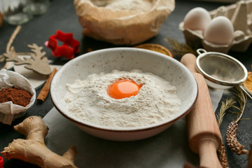The process of making christmas cookies. Girl hands make the dough. Ingredients for baking a pie: flour, confectionery, dishes, kitchen utensils, spruce cookies figure on a dark background.Christmas g