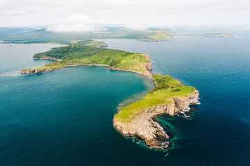 Aerial view of Cape Tobizina, Russky Island near Vladivostok. Green forest at blue sea coast, rocky and steep cliffs, sunny summer day. Seaside nature landscape in Primorsky Krai, Far East, Russia