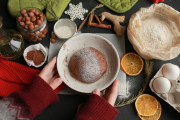 The process of making christmas cookies. Girl hands make the dough. Ingredients for baking a pie: flour, confectionery, dishes, kitchen utensils, spruce cookies figure on a dark background.Christmas g