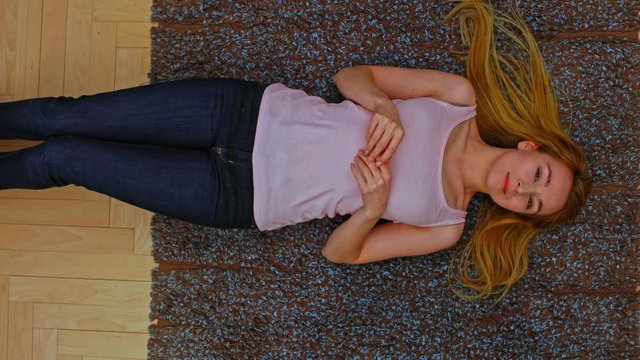Young woman lying on floor in home. She daydreaming. camera is above her.