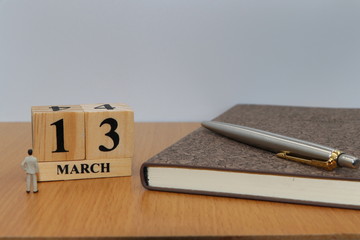 March  13, a calendar photo from the wood The table top consists of a book and pen that is ready to use. White background