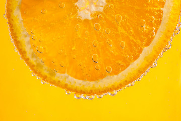 Orange and bubbling water on yellow background. Healthy, still life, summer, drinks concepts.