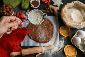 The process of making christmas cookies. Girl hands make the dough. Ingredients for baking a pie: flour, confectionery, dishes, kitchen utensils, spruce cookies figure on a dark background.Christmas g