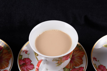 Cup and saucer filled with coffee and milk on a dark cloth background