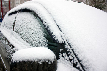 The car is covered with white fluffy snow. Winter