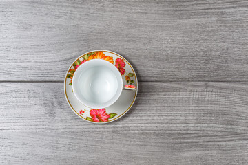 A single empty Cup and saucer on a wooden table