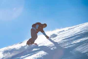 Snowboarder Riding Red Snowboard in Mountains at Sunny Day. Snowboarding and Winter Sports