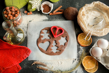 The tradition of celebrating Christmas and New Year. Home bakery cooking traditional holiday sweets. Woman cuts cookies from raw gingerbread dough. Prepare ginger and chocolate cookies together.