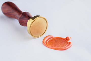 metal head stamp tool with wooden handle and wax seal on white paper