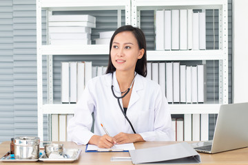 Young attractive female doctor sitting at desk in office at hospital and looking out the window.