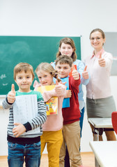 Pupils and teacher showing thumbs-up in school having fun