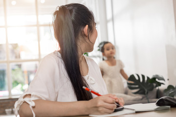 Young Asian beautiful mom with her daugther kid work at home.