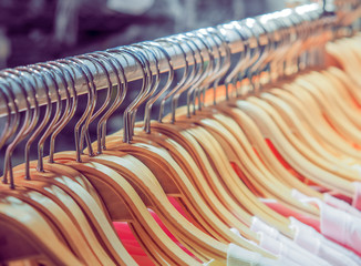 Fototapeta premium Many of wooden clothes hanger on closet or clothing rack in shop for sale. Fashionable clothes in a boutique shop. 