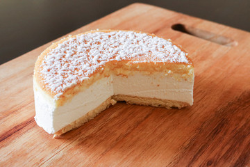 Primo piano di una soffice torta alla ricotta su un tagliere di legno, ricette e dessert