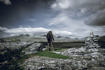 Hiker with backpack looking towards a beautiful mountain scenery.