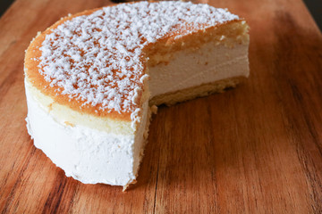 Primo piano di una soffice torta alla ricotta su un tagliere di legno, ricette e dessert