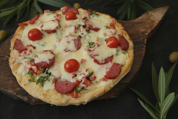 Pepperoni Pizza with Mozzarella cheese, sausages salami, Spices, tomato, olive and branch of olive for decoration. Italian pizza isolated on black background. Food background.