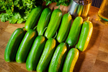 Cucumbers lie on a wooden Board. The use of vegetables in food. Vegetarianism. A raw food diet. The vegetables are beautifully lit. Fresh vegetables. Health food.