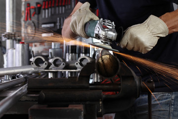 hands man work in home workshop garage with angle grinder, goggles and construction gloves, sanding...