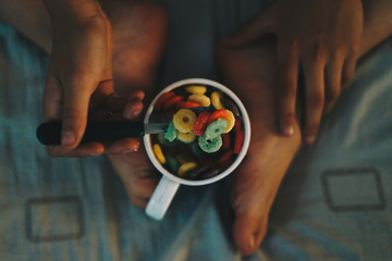 Obraz premium Young child having breakfast and eating colorful cereals in bed.