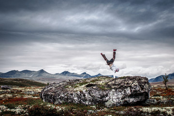 Man doing handstand in mountain scenery.