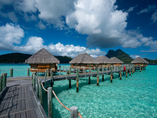 Luxury overwater villas on blue lagoon, white sandy beach and Otemanu mountain at Bora Bora island,...