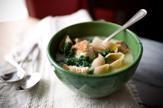 Garlic soup with spinach and shell pasta served in bowl