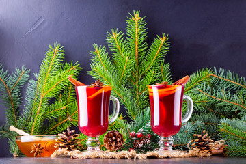 Red mulled wine and fir branches on burlap. Mulled wine with oranges, honey, cinnamon and cloves on...