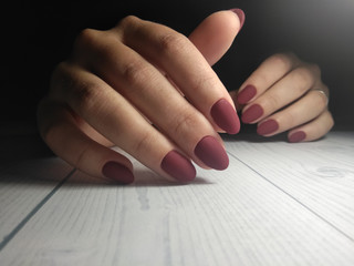 Red matte manicure on women's hands. Wine-colored coating on short round nails.