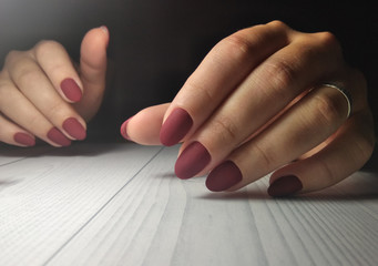 Red matte manicure on women's hands. Wine-colored coating on short round nails.