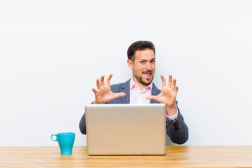 young handsome businessman feeling terrified, backing off and screaming in horror and panic,...