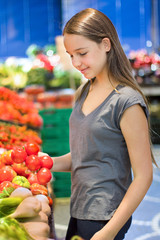  Teen girl shopping in supermarket reading product information. Choosing daily product.  Concept of information eating products, organic fruit and vegetables. 