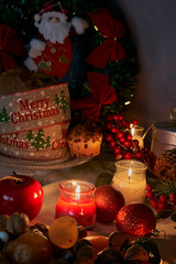 Christmas or New Year in the light of candles with sweets, red and gold ornaments specific for these dates on a white thread tablecloth background.