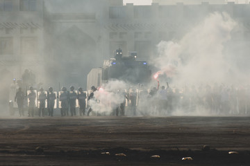Military police riot response to a protest with tear gas, smoke, fire, explosions. Political expression, riot, protest, demostration and military concept.