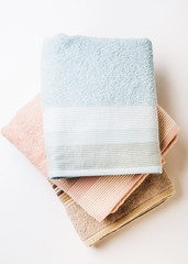 Pastel color clean folded towels on white background. Flat lay