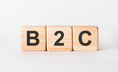 B2C letters of wooden blocks in pillar form on white background, copy space