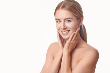 Beautiful healthy young woman full of vitality holding her hands to her cheeks to shield her breasts as she gives the camera a lovely radiant smile