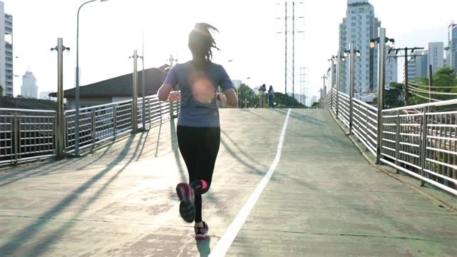 Female young Asian athlete running on the street in the city. Training cardio jogging workout lifestyle on the street at sunset. Healthy lifestyle.