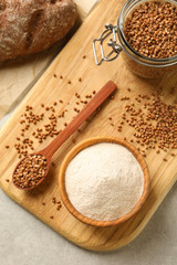 Flat lay composition with bowl of buckwheat flour and grains on grey table
