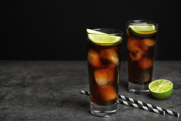 Refreshing soda drinks with straws on grey table against black background, space for text